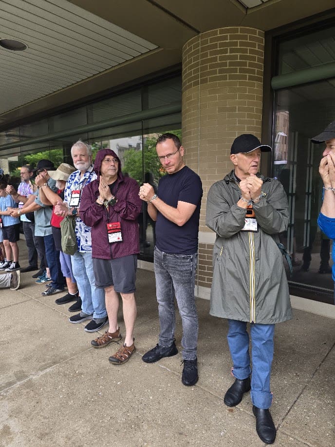 More than 200 magicians standing in rows across a rain-soaked public plaza, each wrapped in chains during a mass escape attempt